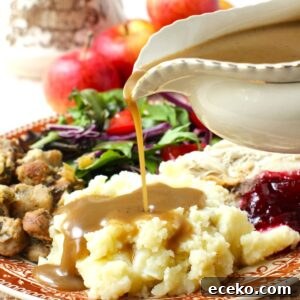Thumbnail photo of gravy boat pouring apple cider gravy onto a mound of mashed potatoes on a plate full of turkey dinner.