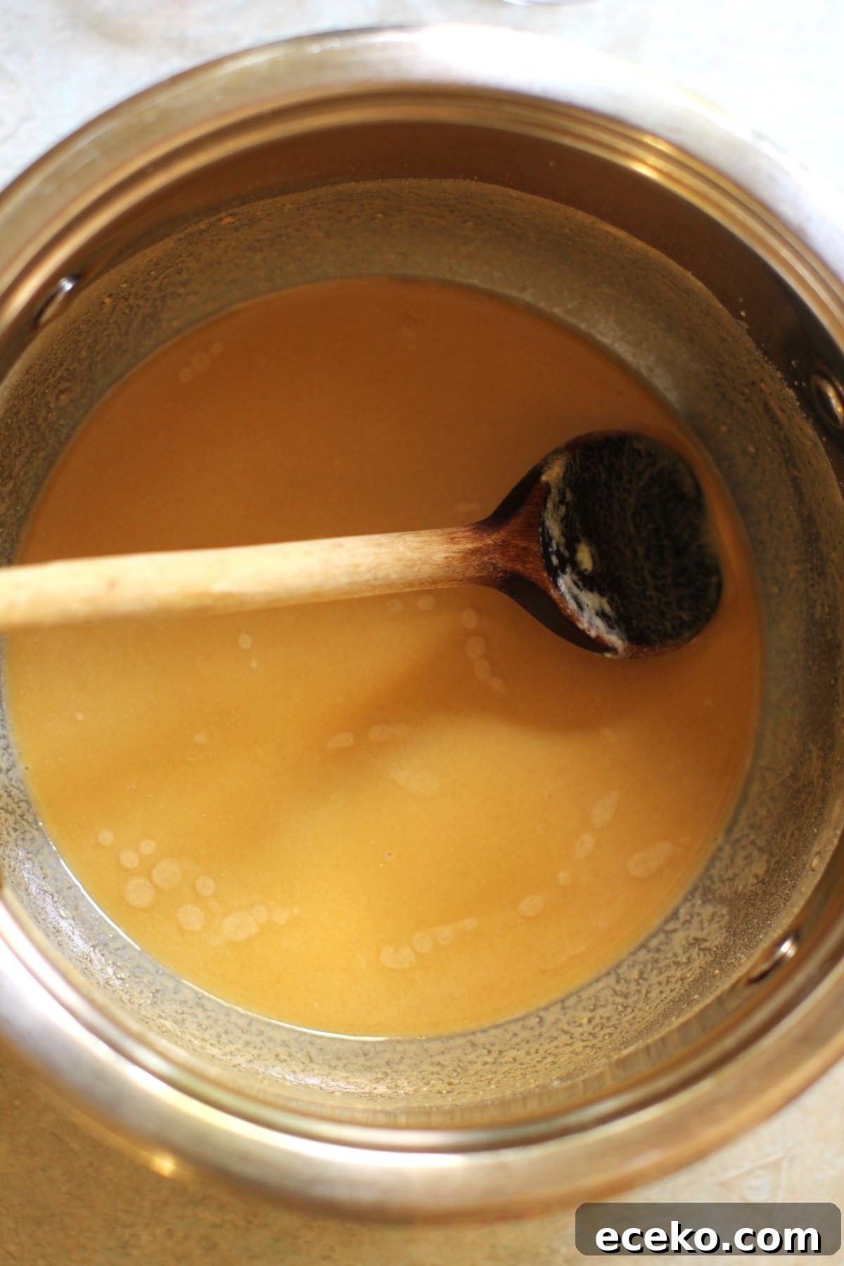 Cooking the roux to a rich golden-brown colour in a saucepan with a wooden spoon.