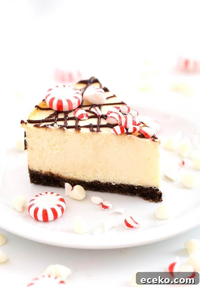 Slice of White Chocolate Peppermint Cheesecake on white plate garnished with broken peppermint candies