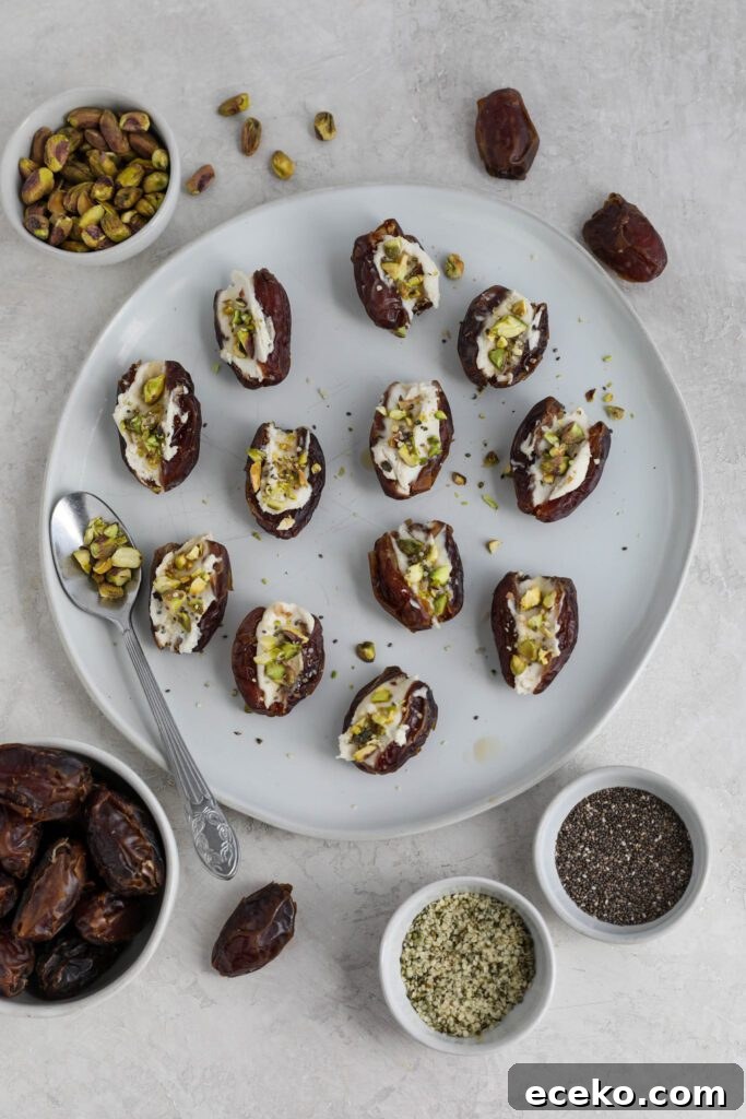 Dates stuffed with cream cheese and topped with pistachios, hemp hearts, and chia seeds on white plate