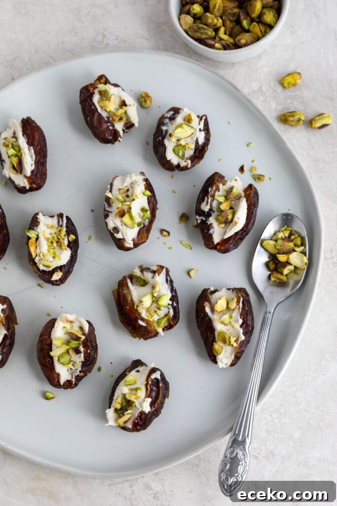 Dates stuffed with cream cheese and topped with pistachios on white plate