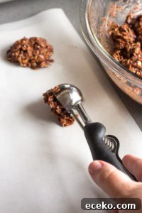 No-Bake Chocolate Peanut Butter Oatmeal Cookies – Gluten Free 9 placing a scoop of no bake chocolate oatmeal peanut butter cookies onto parchment paper