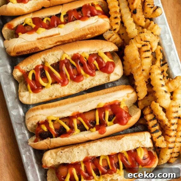 Smoky Burnt Ends Hot Dogs: Crispy, Charred BBQ Bites 14 Hot dogs topped with a drizzle of mustard and ketchup on a platter with a side of french fries.