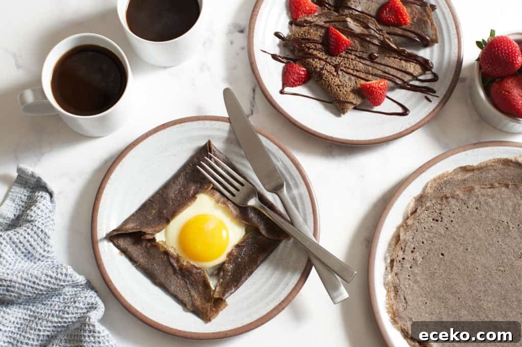 Plates of sweet and savory buckwheat crepes, one with an egg folded in French galette style, the other folded in triangles with chocolate and strawberries. Two cups of coffee and a blue napkin are to the left.