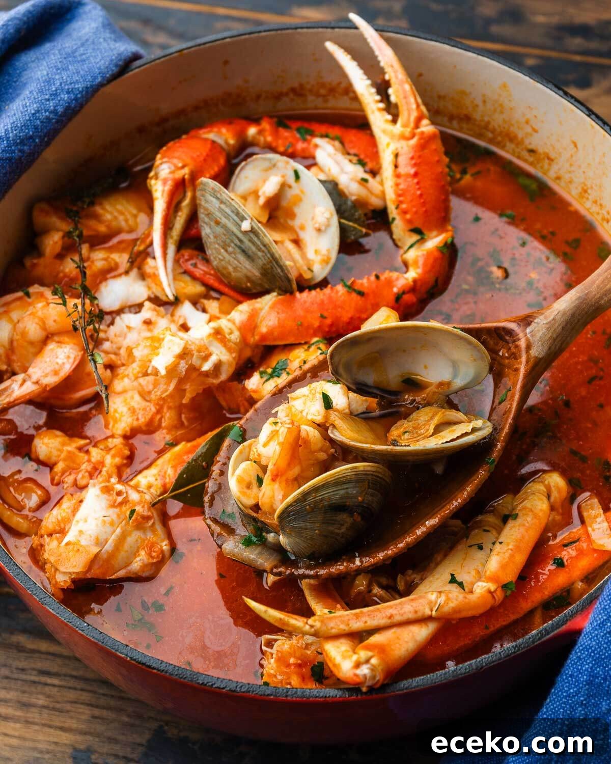 Authentic Cioppino: San Francisco-Style Seafood Steewith Shellfish 2 Wooden ladle holding clams and shrimp above pot of cioppino.