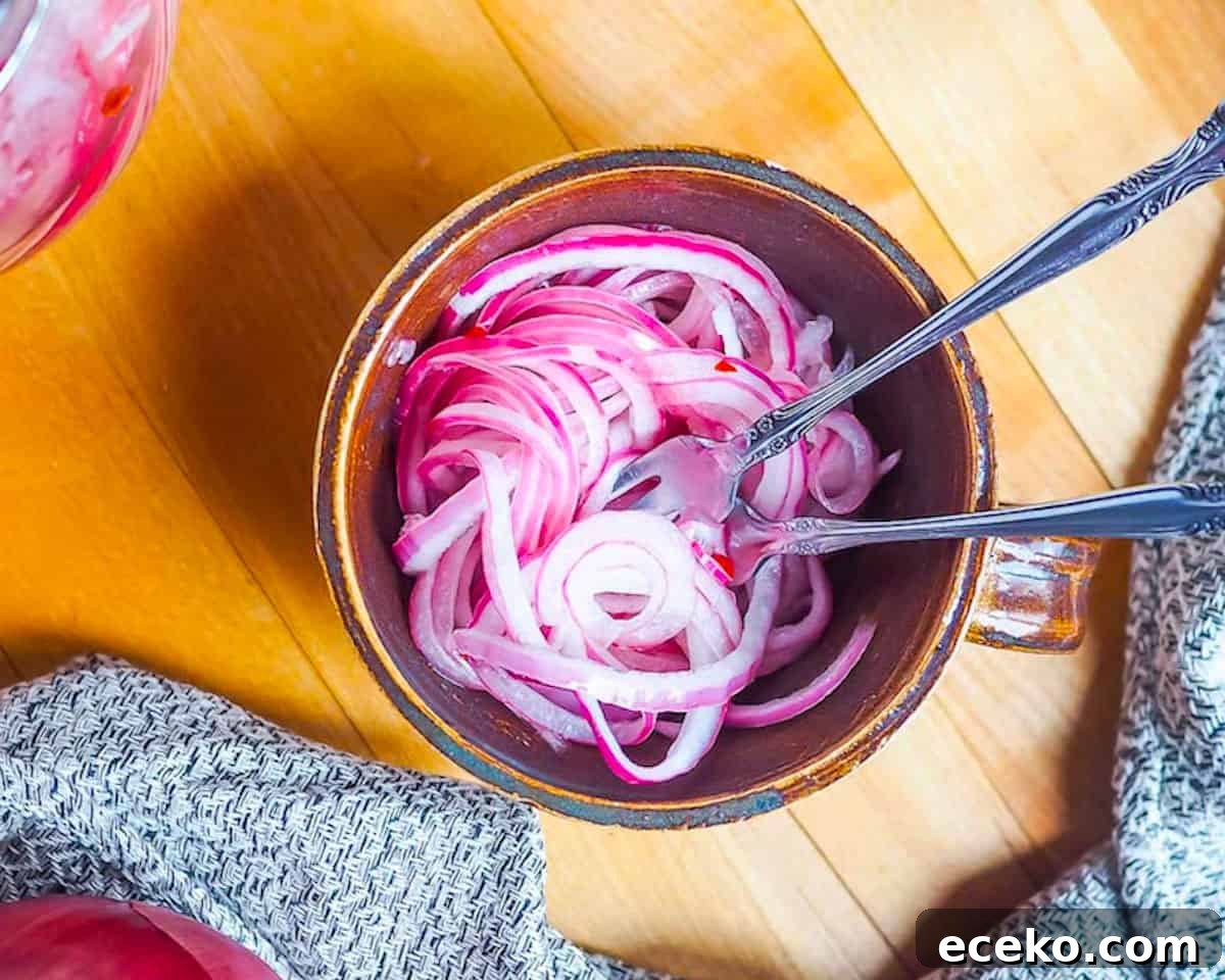Quick Pickled Red Onions Recipe for Toppings & Salads 2 A small brown mug with pickled red onions and two small forks in it.