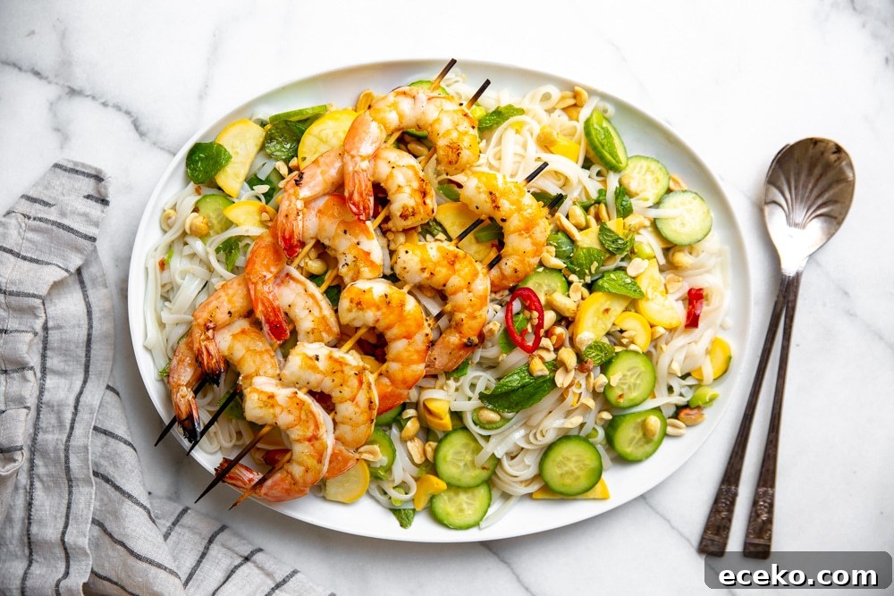 Vietnamese Cold Rice Noodle Salad with Garlicky Shrimp Skewers 9 Rice noodle salad with shrimp on a platter, with serving spoons alongside.