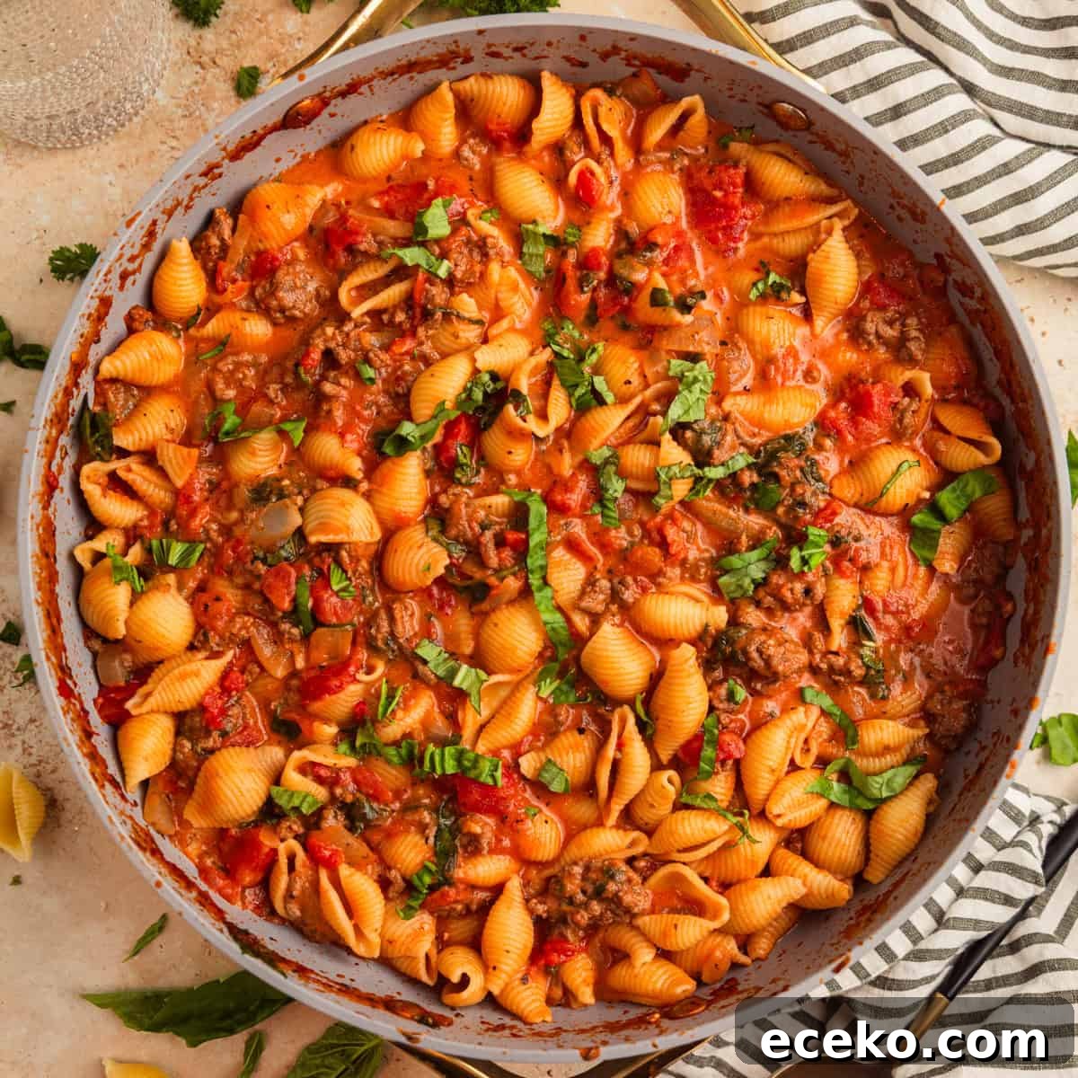 Ground beef pasta in skillet topped with basil.