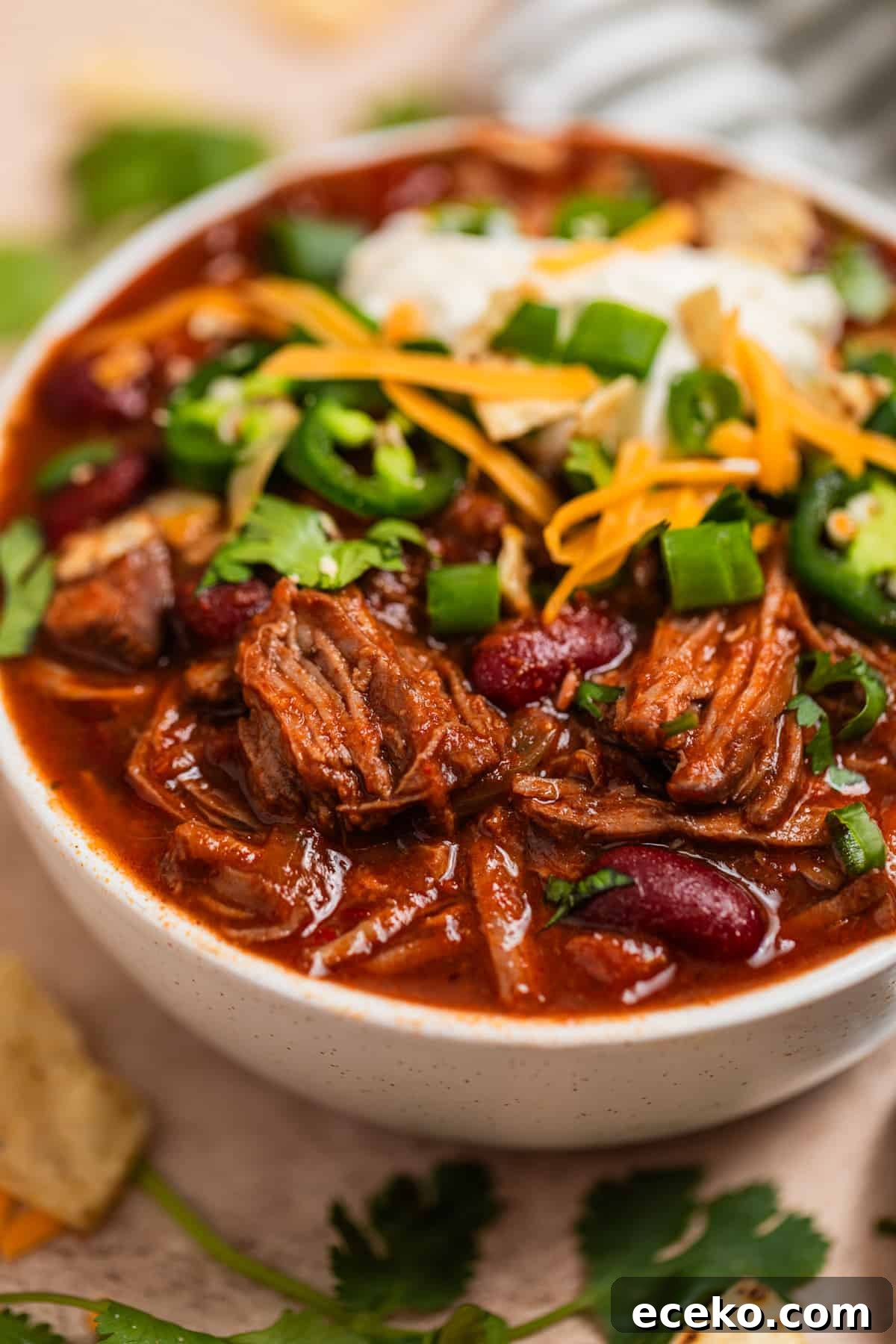 Bowl of crockpot chili topped with sour cream, cheese and other toppings.