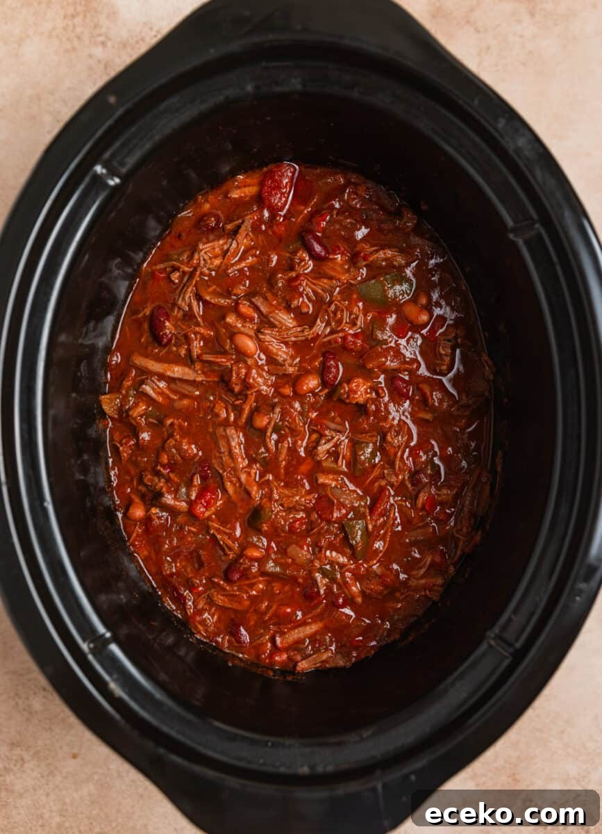 Shredded beef chili in crockpot after freshly shredded beef is added into the pot.