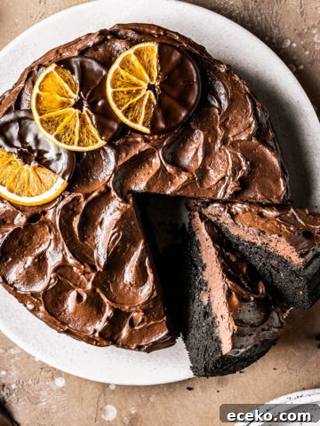 A chocolate cake with two slices cut and tipped revealing the dark interior and fudgy chocolate frosting.
