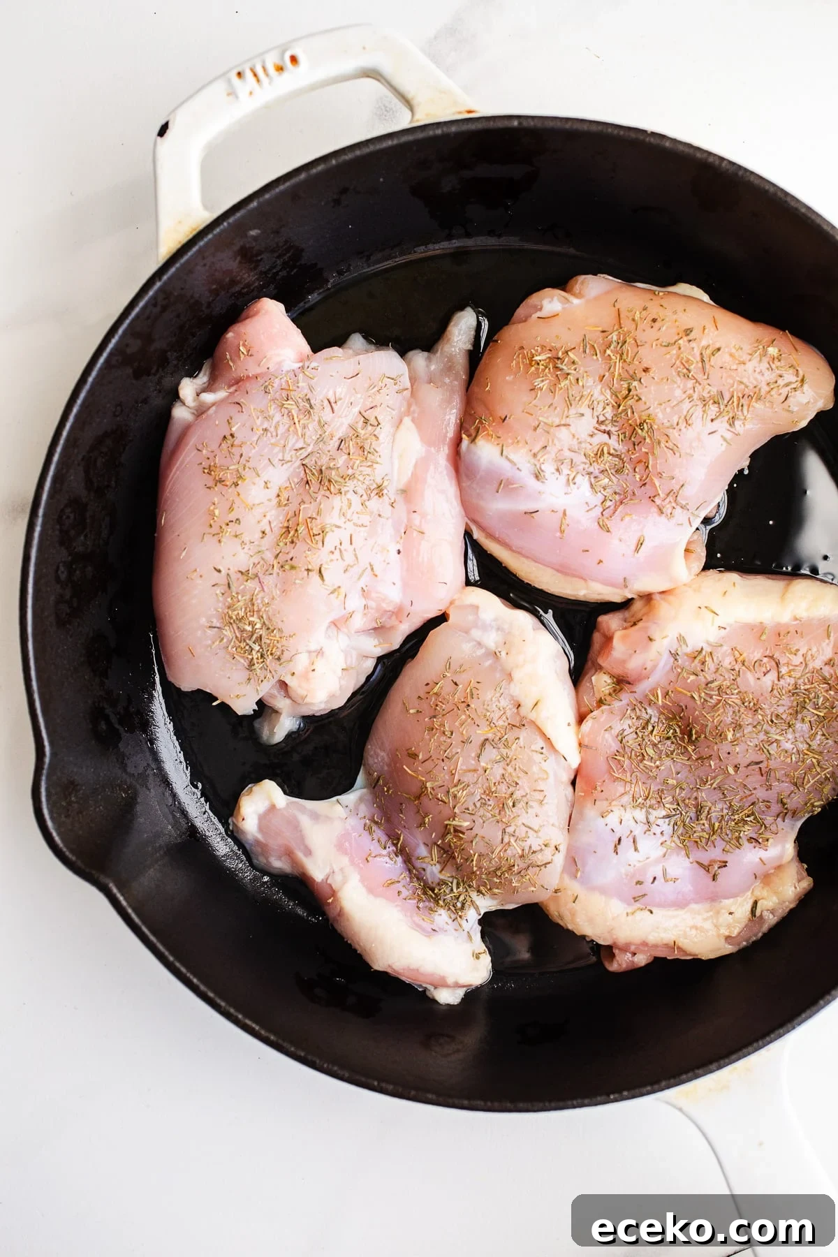 Raw chicken in a skillet.
