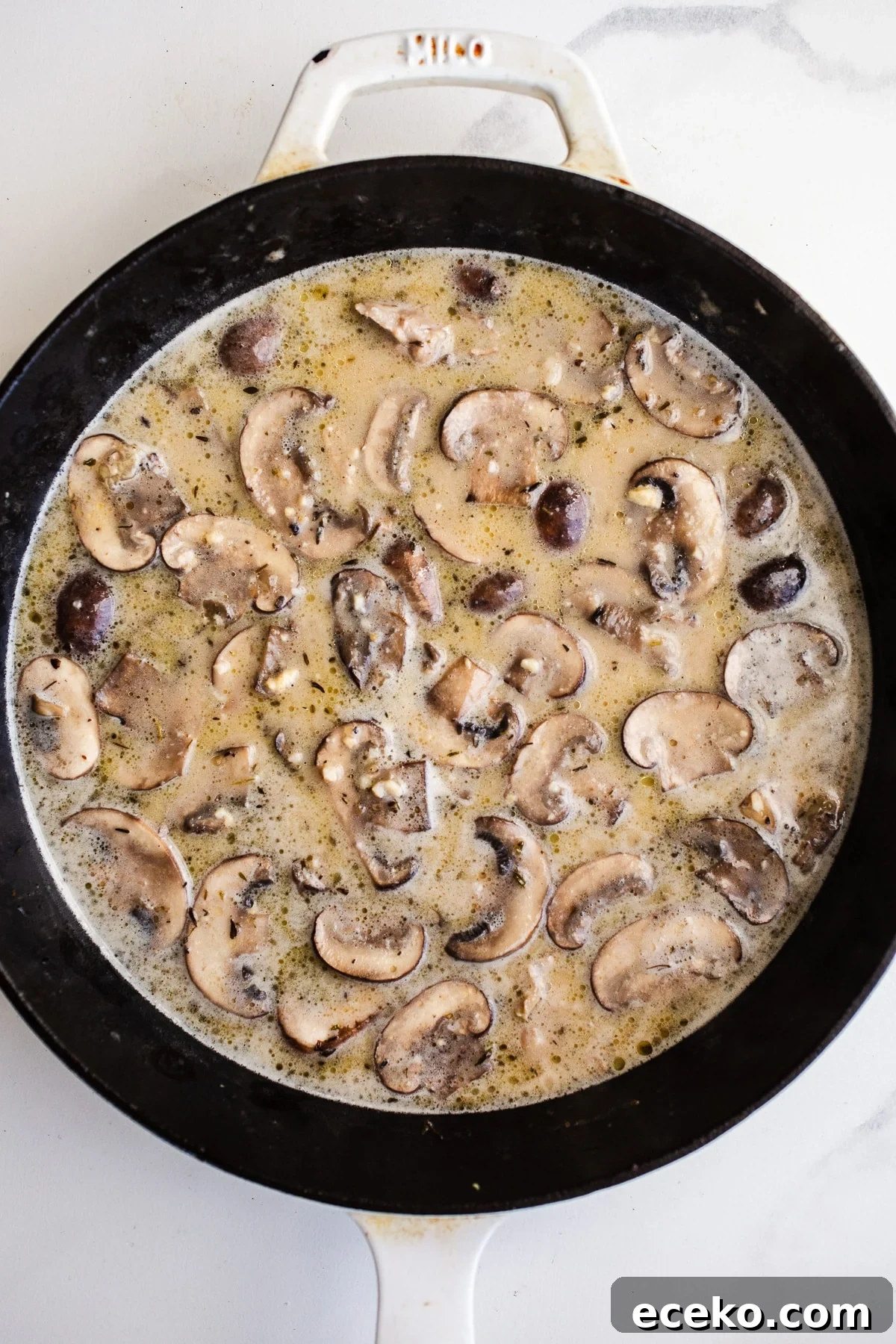 Coconut milk, broth, and mushrooms in a skillet.