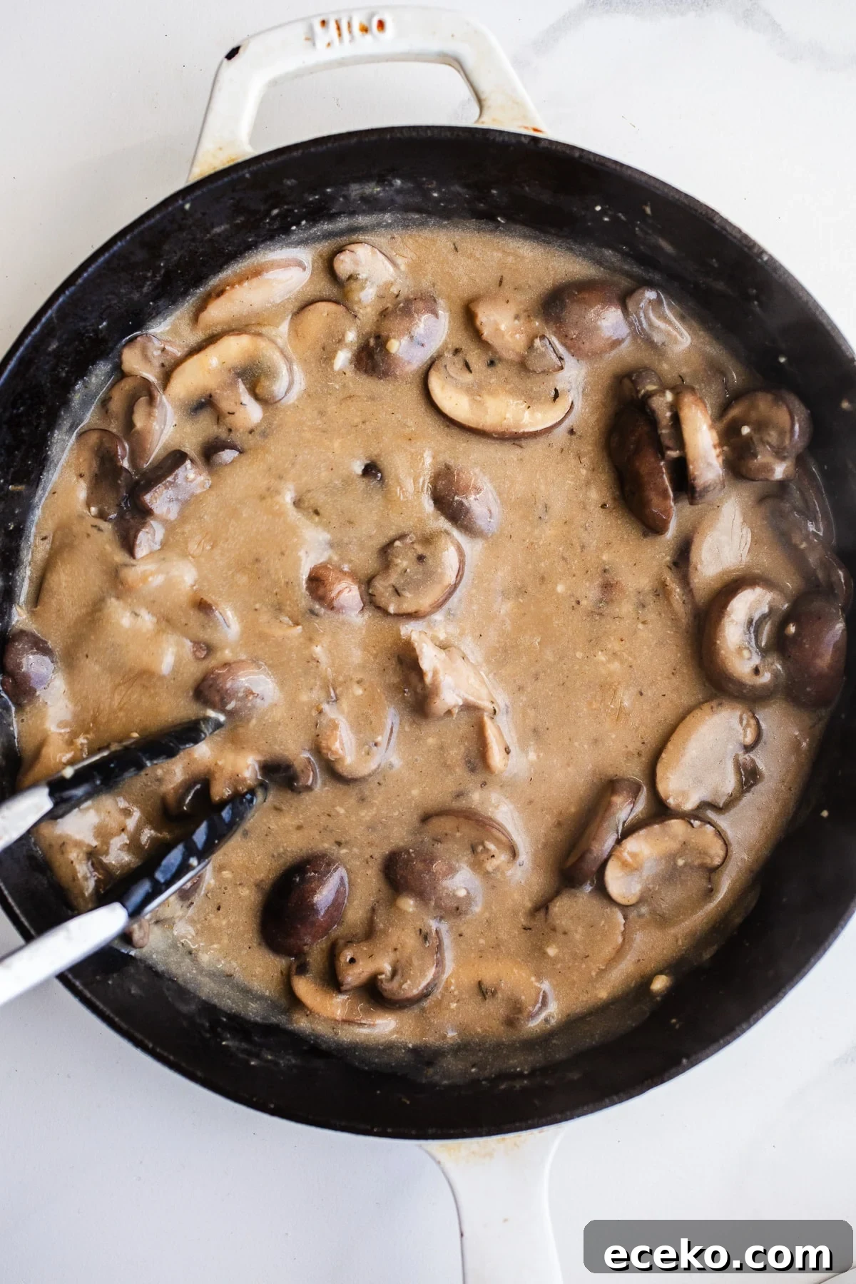 Sauce and mushrooms in a skillet.