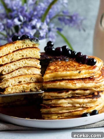 A plate with a stack of sourdough discard pancakes with a slice of them taken out.