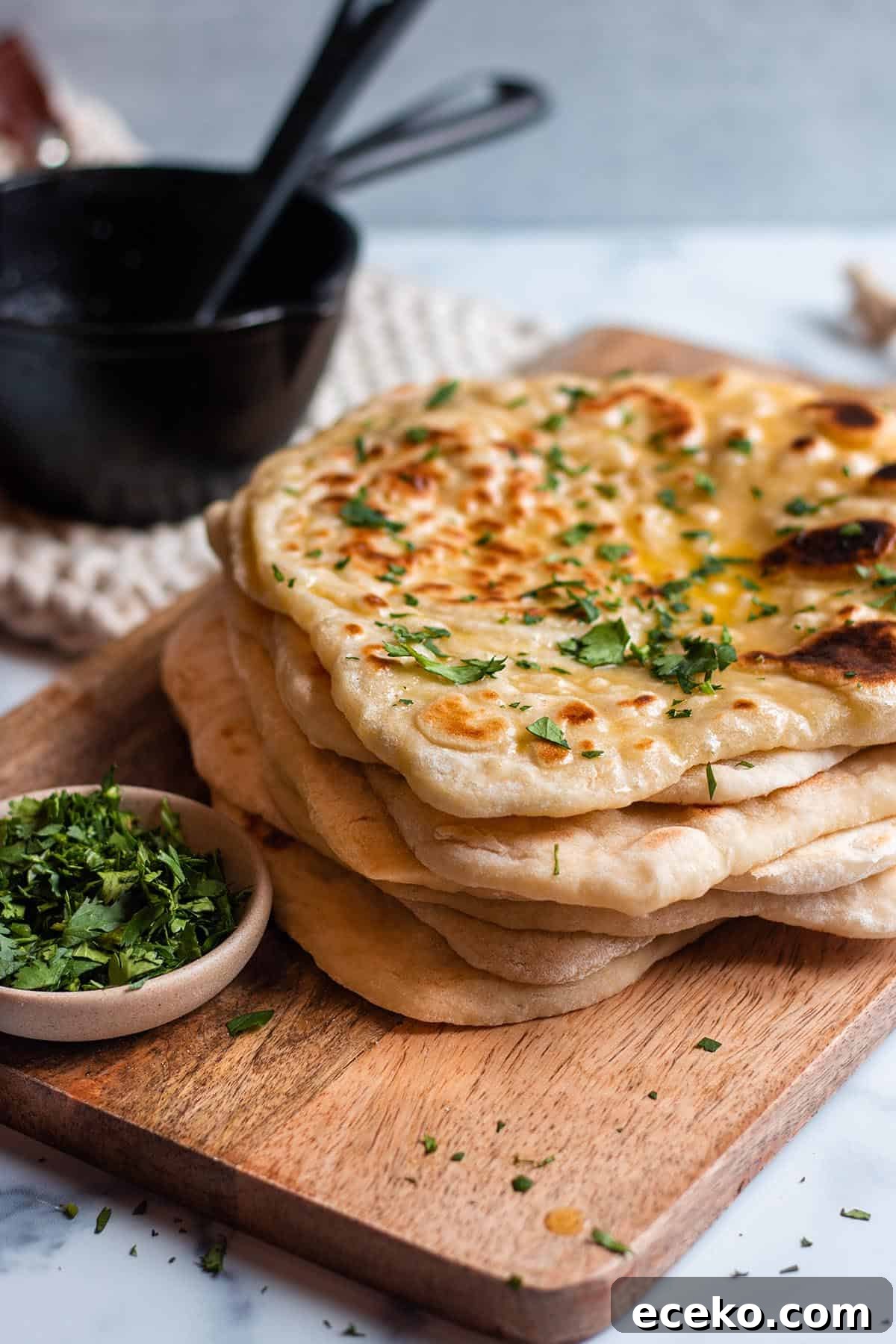 Naan flatbread with fresh parsley and melted butter on a wooden board.