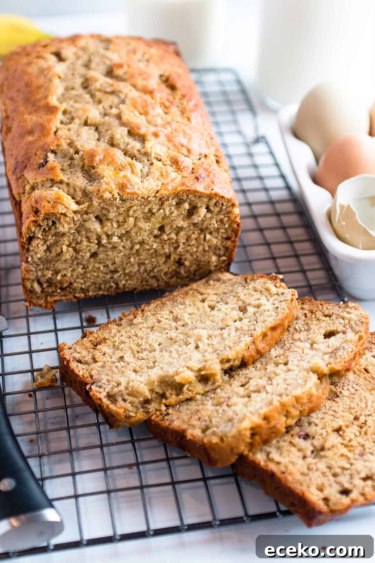 A loaf of banana bread on a cooling rack cut into slices.