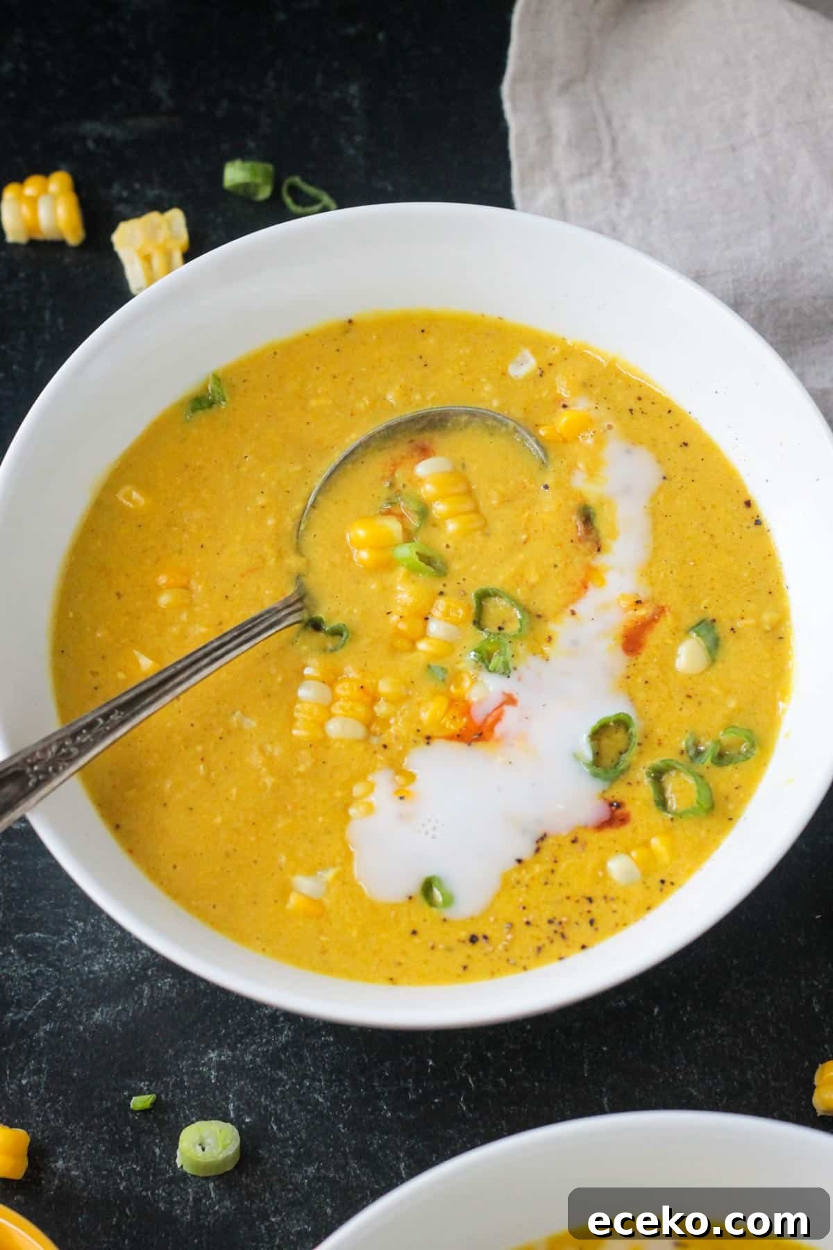 Creamy Coconut Curry Corn Soup Recipe 11 A spoon in a bowl of curried corn soup.