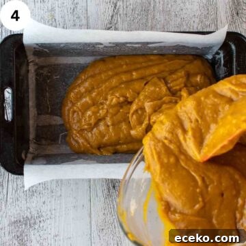 Orange batter being poured into a loaf pan.