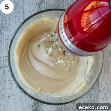 Creamy frosting being beating with an electric mixer.