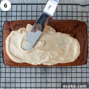 Creamy frosting being spread on a loaf cake.