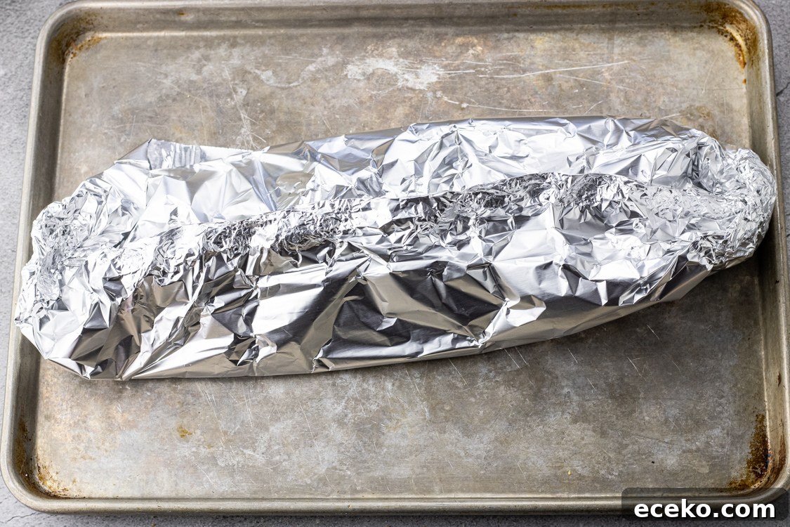 salmon wrapped in foil on a baking sheet