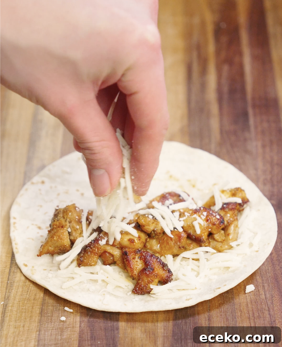 Crispy Chicken Tacos Recipe with Zesty Slaw and Lime крем 7 Crispy pan-seared chicken pieces placed onto a warm flour tortilla with shredded cheese, forming the base of homemade crispy chicken tacos.