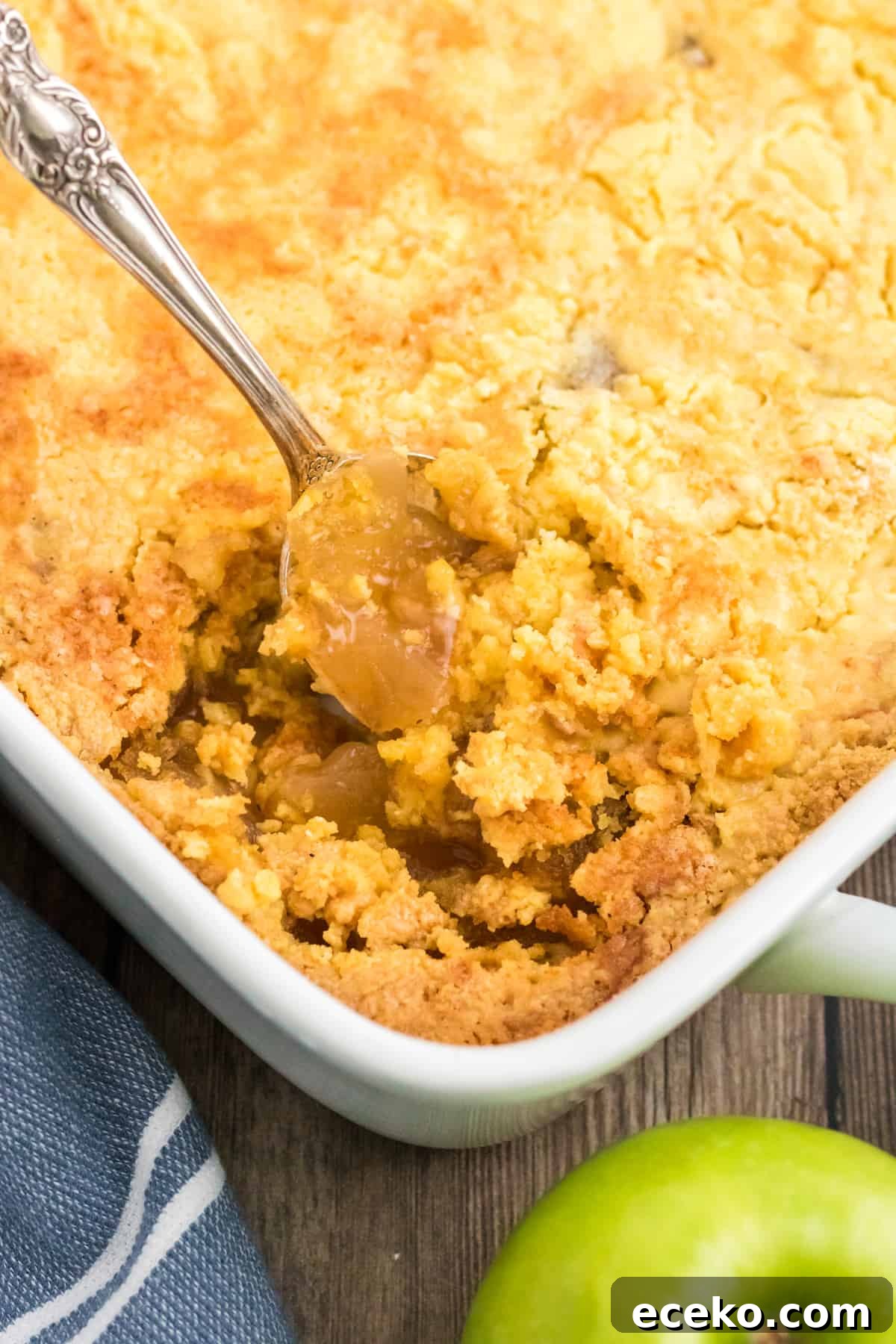 3-Ingredient Apple Dump Cake Recipe: Quick Crowd-Pleasing Dessert 3 Spoon scopping out apple dump cake from casserole dish.