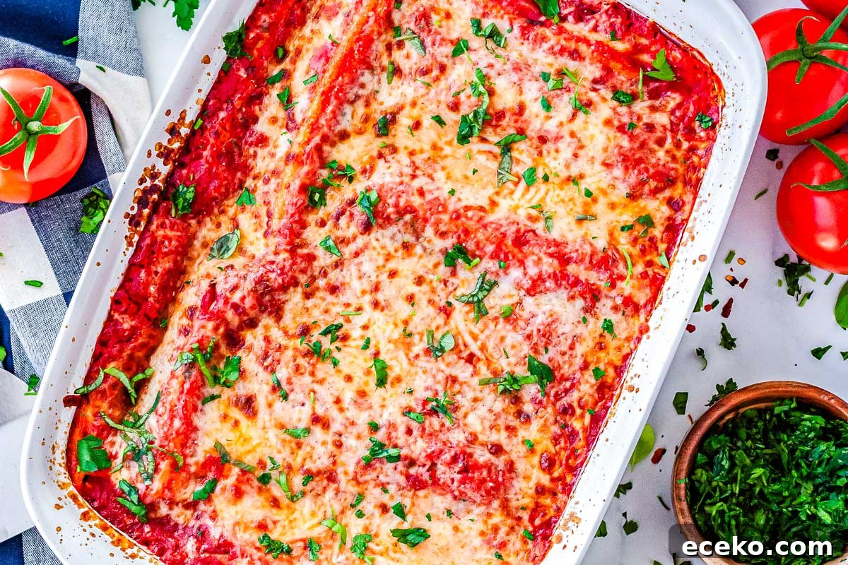 Three-Cheese Manicotti with Homemade Tomato Sauce 3 An overhead view of the full baked casserole dish, featuring golden melted cheese, rich tomato sauce, and a garnish of fresh chopped basil.
