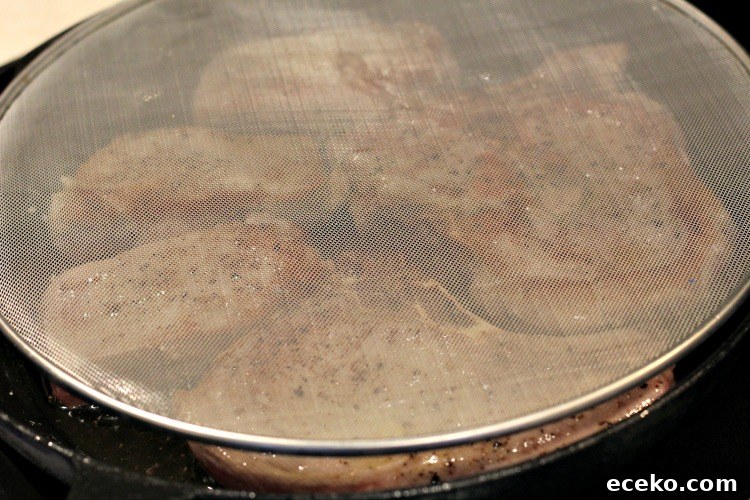 Garlic Butter Pork Chops in a Cast Iron Skillet Recipe 6 Bacon Splatter screen on skillet with pork chops cooking