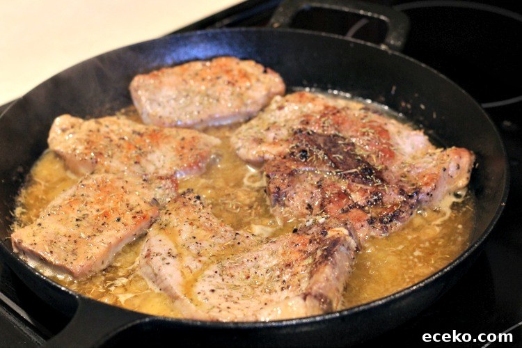 Garlic Butter Pork Chops in a Cast Iron Skillet Recipe 8 Garlic Butter Pork Chops almost done cooking in skillet on stove top