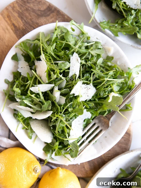 Crispy Homemade Croutons Recipe for Salads and Soups 9 White plate with arugula and shaved parmesan salad tossed in a light lemon dressing.
