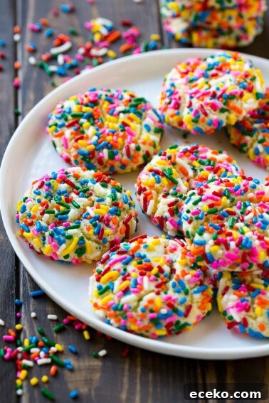 A plate of funfetti cookies coverd in rainbow sprinkles.