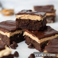 one zucchini brownie with peanut frosting on top of two other ones and chocolate chips around