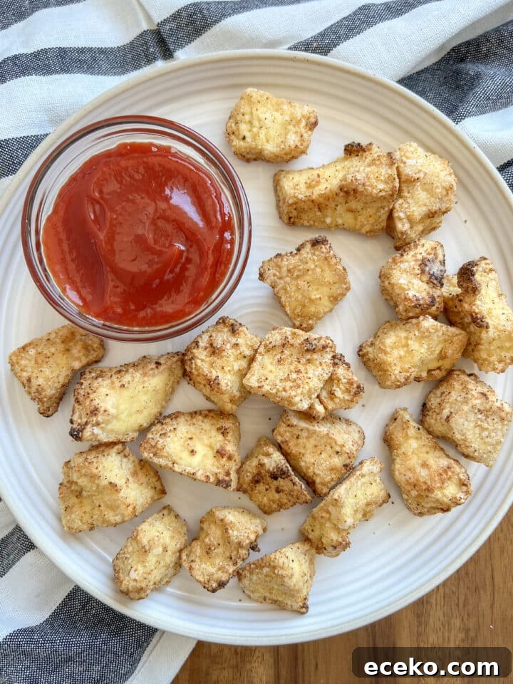 Crispy Air Fryer Tofu Nuggets — Quick Weeknight Recipe 3 air fryer tofu nuggets on a white plate with a small bowl of ketchup
