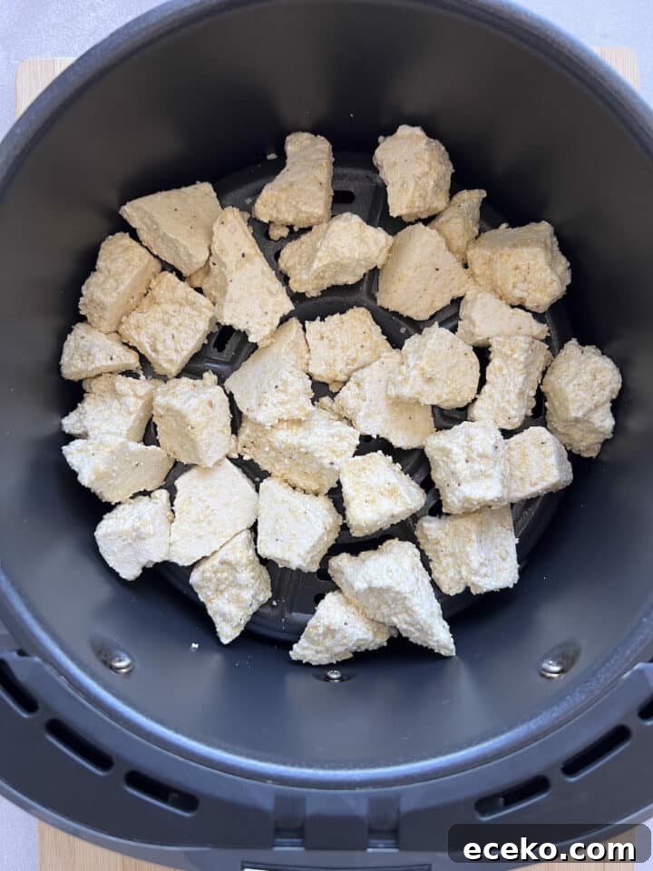 Crispy Air Fryer Tofu Nuggets — Quick Weeknight Recipe 9 Coated tofu chunks raw in an air fryer basket