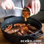 Cowboy Stew Recipes: Campfire, Stovetop, Oven & Slow Cooker Methods 20 womans hands spooning baked beans from a can into a pan of sausages for a campfire stew
