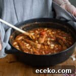 Cowboy Stew Recipes: Campfire, Stovetop, Oven & Slow Cooker Methods 21 woman holding a small Dutch oven of cowboy sausage stew