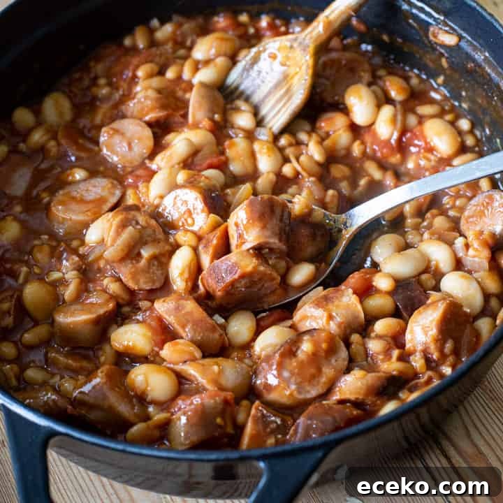 Cowboy Stew Recipes: Campfire, Stovetop, Oven & Slow Cooker Methods 4 overhead shot inside a black cast iron pan of cowboy casserole with beans and chopped sausages