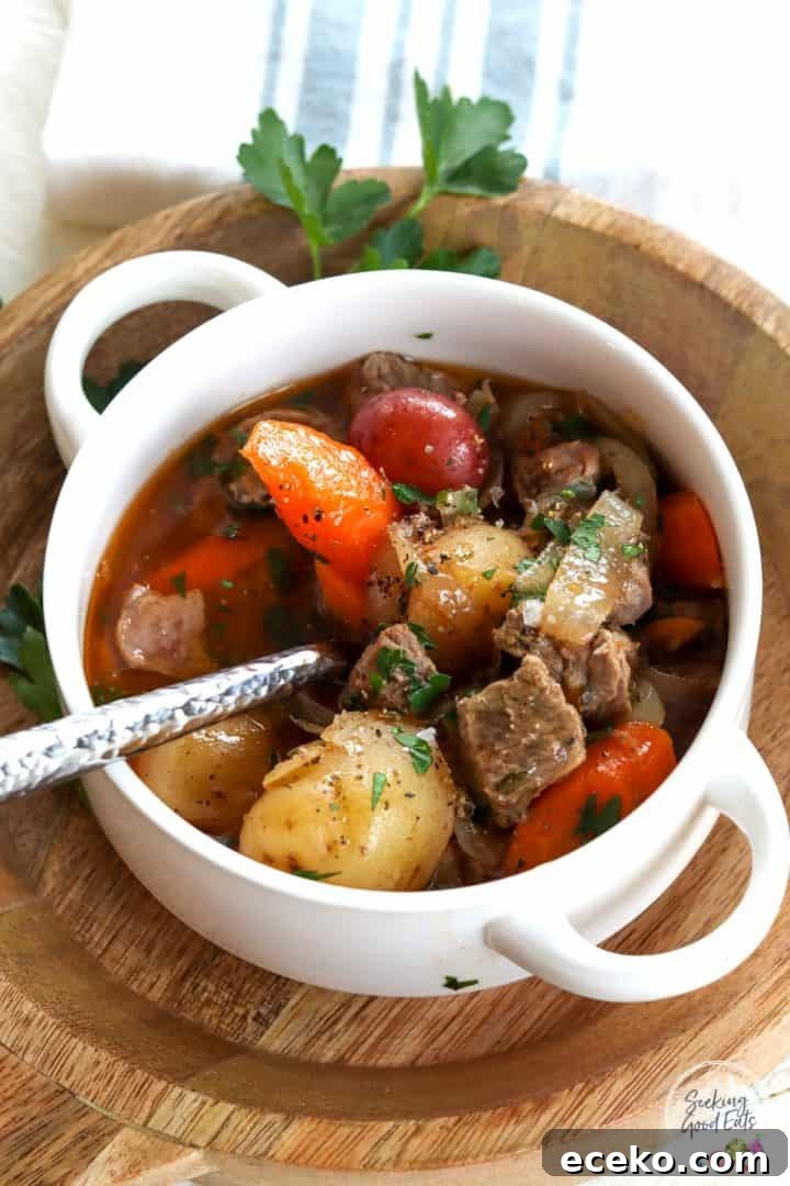 Slow Cooker Irish Lamb Stew Recipe 2 Slow cooker irish stew served in a white bowl with handles and garnished with pepper and parsley.