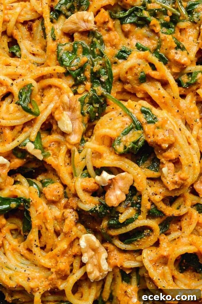 20-Minute Creamy Vegan Pumpkin Pasta Recipe 3 Close up of spaghetti with orange sauce walnut halves and wilted spinach
