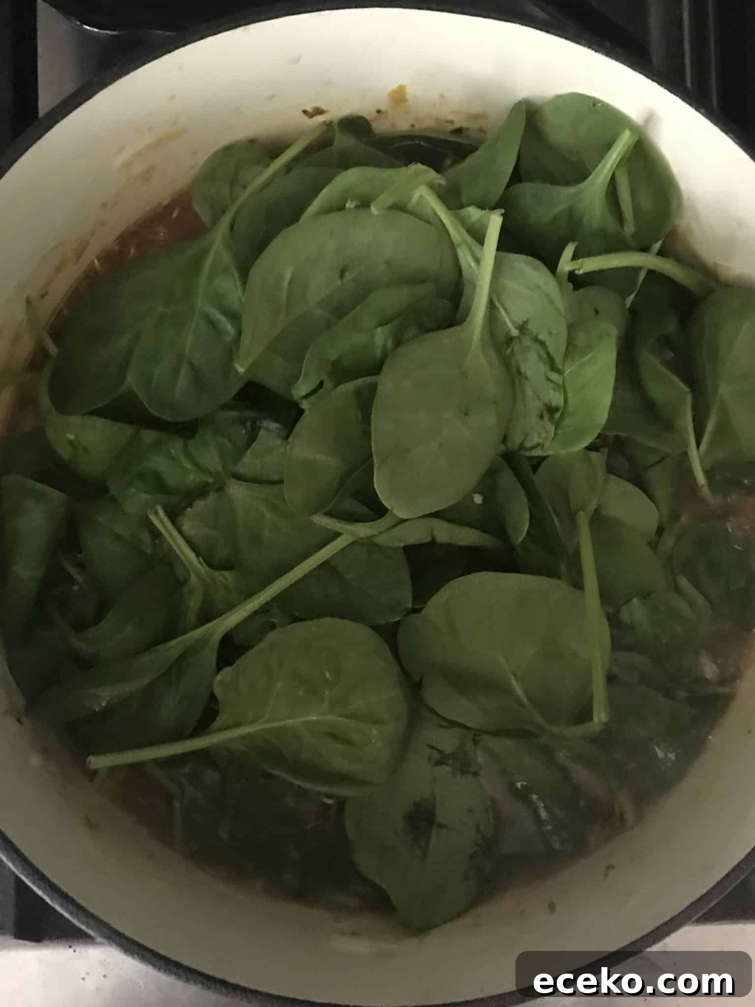 Spinach added to soup pot overhead shot