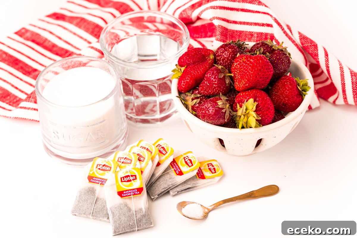 Refreshing Iced Strawberry Tea Recipe for Summer Infusions 4 ingredients used to make strawberry sweet tea on a white table with a white and red striped napkin.