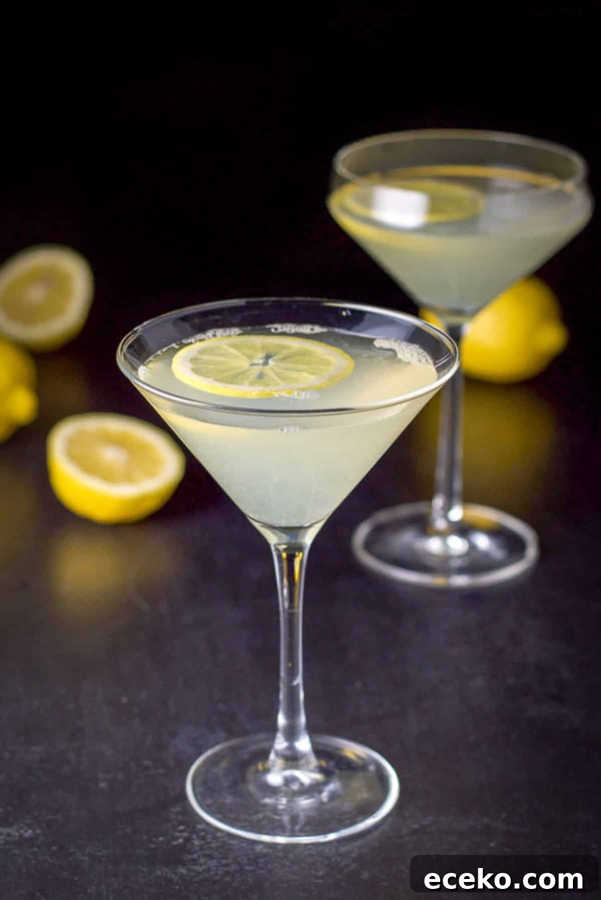 Lemon wheels floating in two martini glasses filled with the lemon cocktail