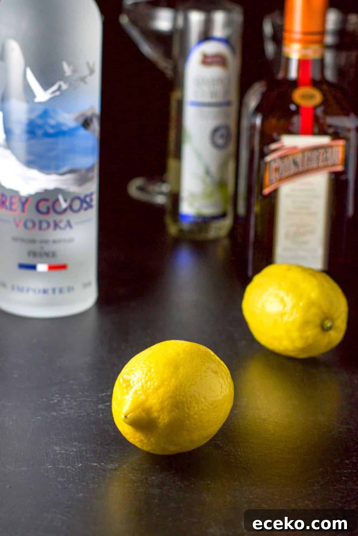Lemon, vodka, Cointreau and simple syrup and the glassware and shaker in the background