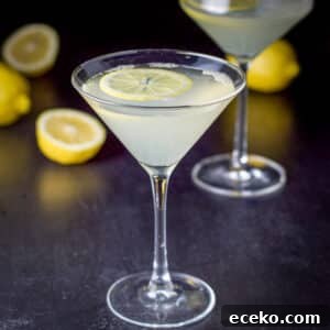 The classic martini filled with the lemon martini with lemon wheels floating in it and lemons on the table