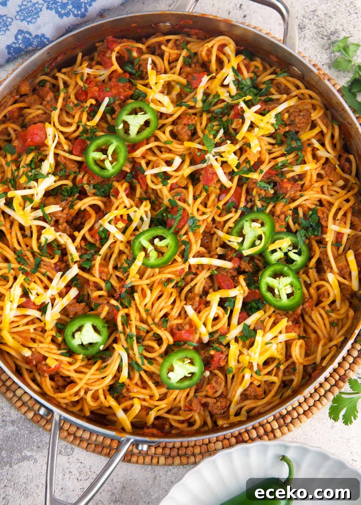 Taco Spaghetti Recipe: Spicy Mexican-Italian Fusion Pasta 4 Taco Spaghetti in a skillet topped with jalapeno slices.