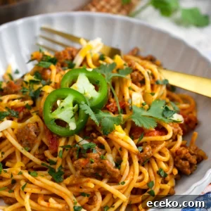 Taco Spaghetti Recipe: Spicy Mexican-Italian Fusion Pasta 7 Taco spaghetti in a white bowl with a gold fork.