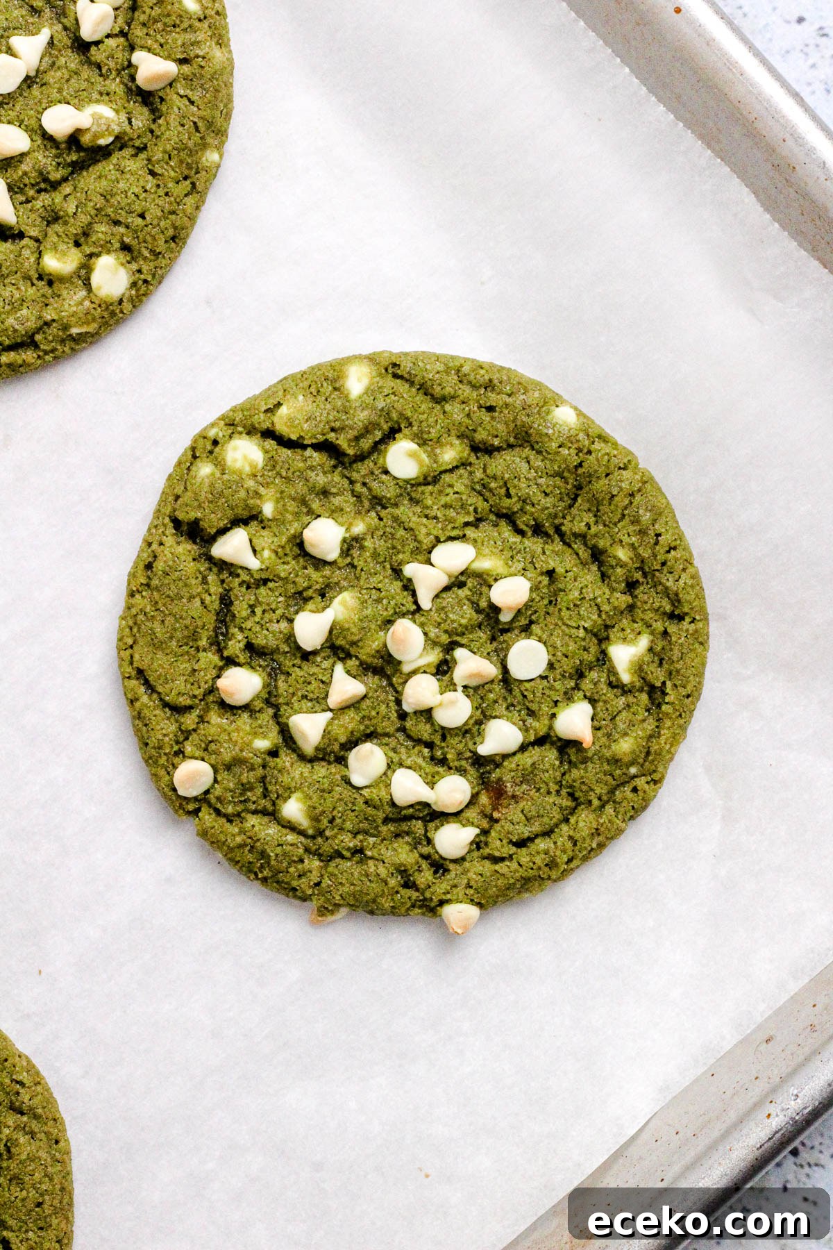 Matcha cookies with white chocolate chips on a parchment lined baking sheet.