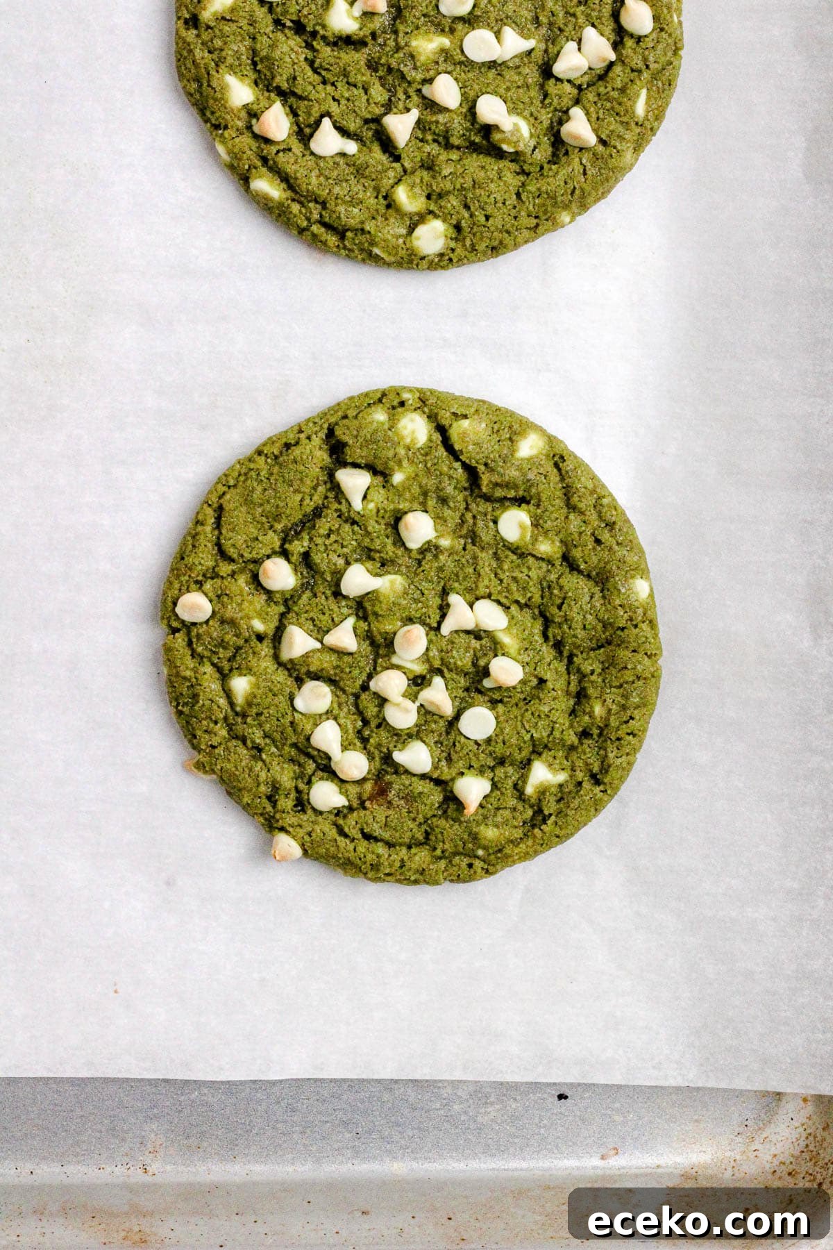 Matcha cookies with white chocolate chips on a parchment lined baking sheet.